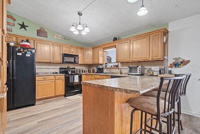 kitchen featuring decorative backsplash, kitchen peninsula, black appliances, pendant lighting, and light hardwood / wood-style floors