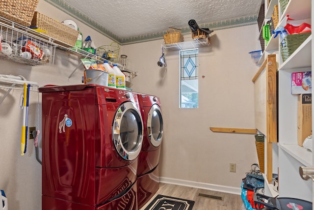 laundry room featuring washing machine and clothes dryer, crown molding, light hardwood / wood-style floors, and a textured ceiling