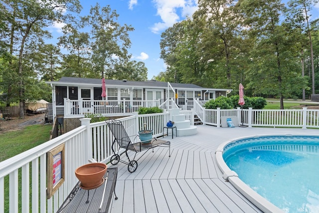 view of swimming pool with a wooden deck and a sunroom