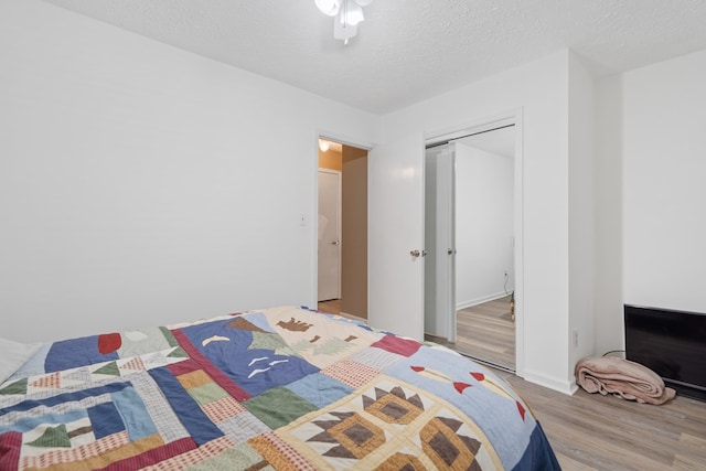 bedroom with hardwood / wood-style flooring, ceiling fan, a textured ceiling, and a closet