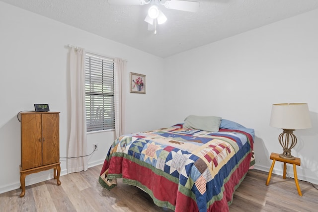 bedroom with a textured ceiling, light hardwood / wood-style flooring, and ceiling fan