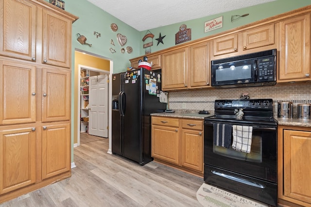 kitchen featuring a textured ceiling, light wood-type flooring, tasteful backsplash, and black appliances