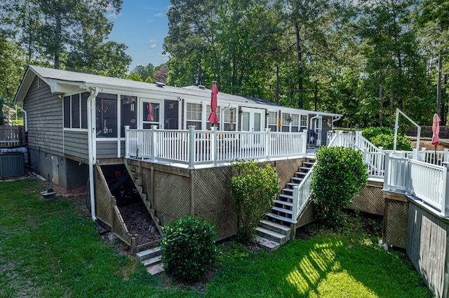 rear view of house with a lawn, a sunroom, central AC unit, and a deck