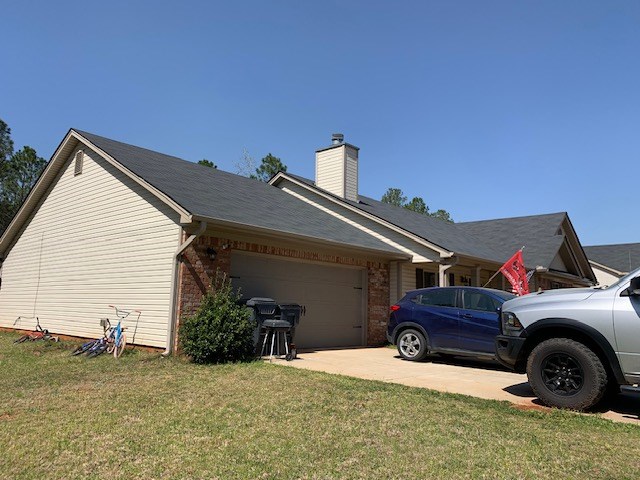 1683 Sara Hunter Ln, Milledgeville, GA 31061 - view of home's exterior featuring an attached garage, a lawn, driveway, a chimney, and brick siding