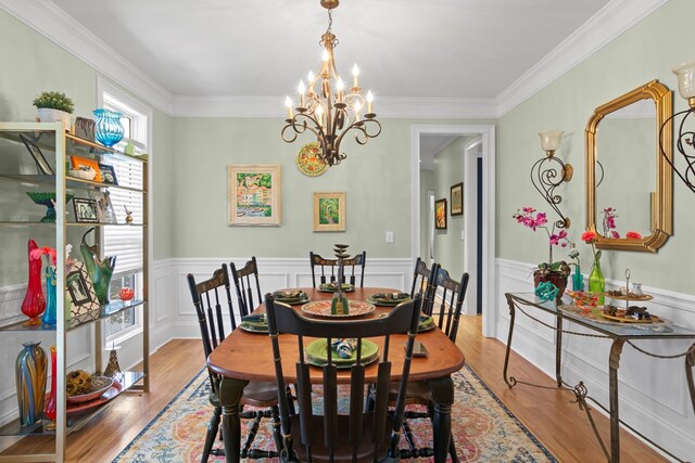 dining space with hardwood / wood-style floors, ornamental molding, and a chandelier