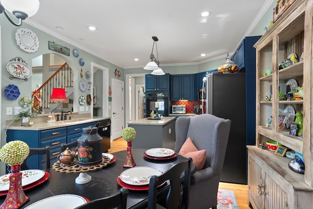 dining room with sink, light hardwood / wood-style flooring, and ornamental molding