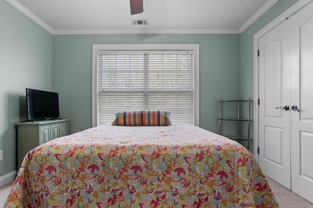 carpeted bedroom with ornamental molding, ceiling fan, and a closet