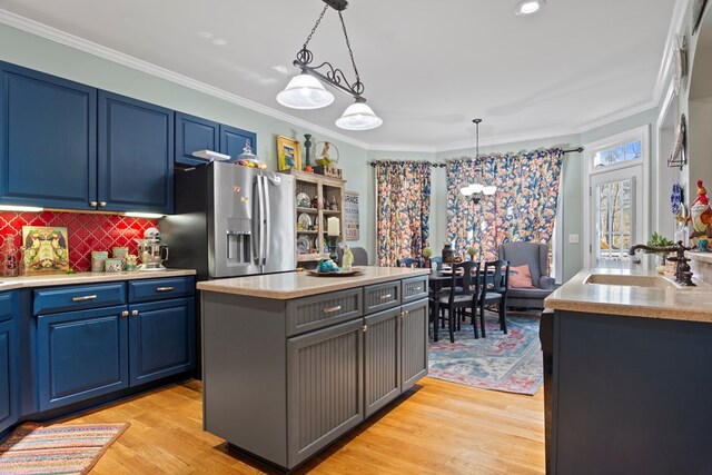 kitchen featuring a center island, sink, hanging light fixtures, stainless steel fridge with ice dispenser, and light wood-type flooring