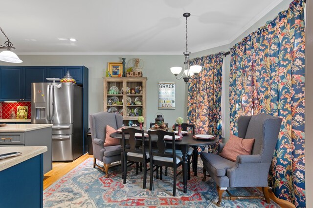 dining room featuring light hardwood / wood-style floors, ornamental molding, and a notable chandelier