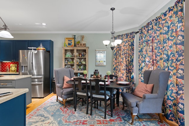 dining space with crown molding, a notable chandelier, and light wood-type flooring