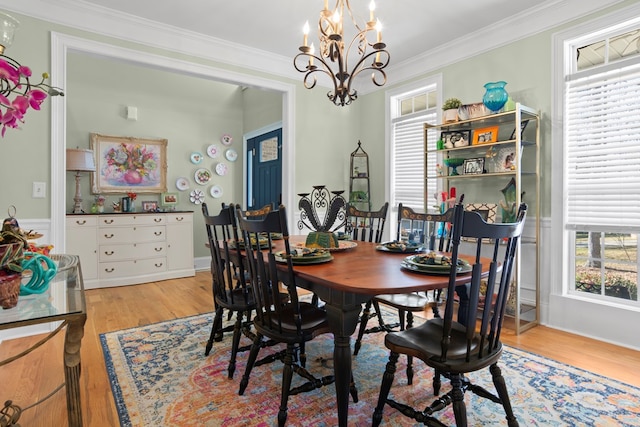 dining space featuring an inviting chandelier, ornamental molding, and light wood-type flooring