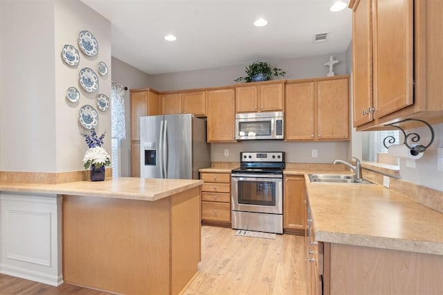 kitchen with appliances with stainless steel finishes, sink, light wood-type flooring, and kitchen peninsula