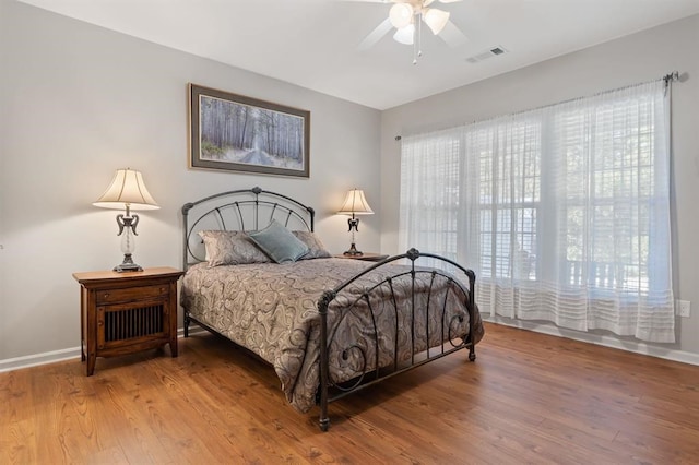 bedroom featuring ceiling fan, wood-type flooring, and multiple windows