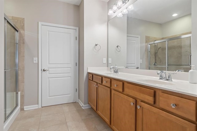 bathroom with a shower with door, vanity, and tile patterned flooring