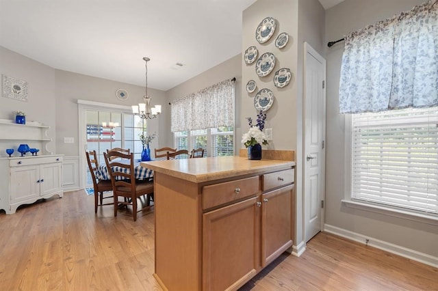 kitchen with a notable chandelier, decorative light fixtures, kitchen peninsula, and light wood-type flooring