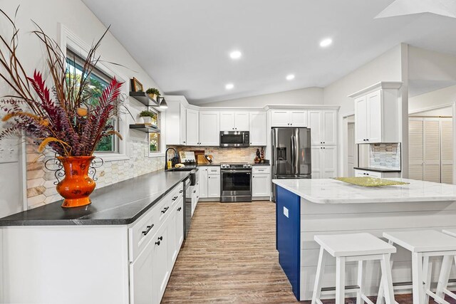 kitchen featuring a center island, light hardwood / wood-style flooring, blue cabinets, backsplash, and white cabinets