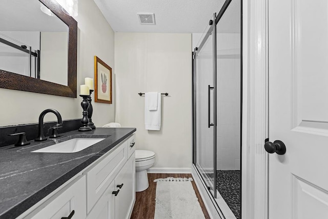 full bath featuring a stall shower, visible vents, toilet, wood finished floors, and vanity