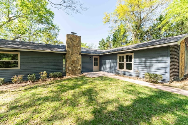 back of property with a lawn and a chimney