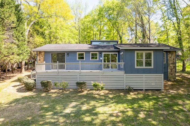 view of front facade featuring a deck, a front lawn, and board and batten siding