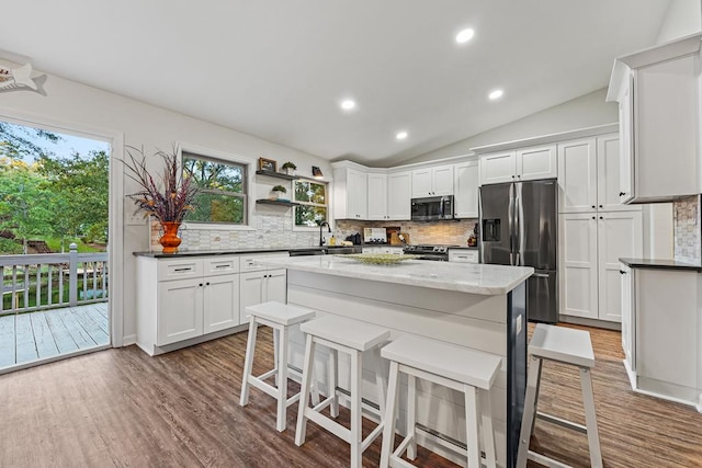 kitchen featuring appliances with stainless steel finishes, decorative backsplash, a center island, and white cabinets