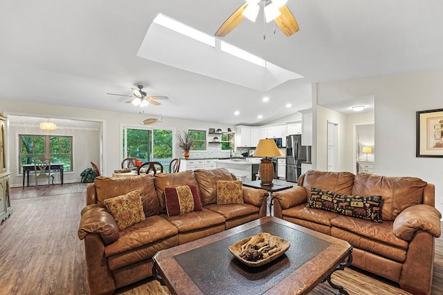 living room with lofted ceiling with skylight, ceiling fan, wood finished floors, and recessed lighting