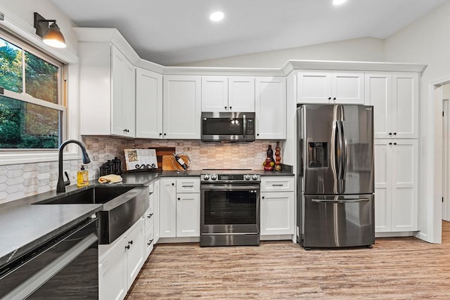 kitchen featuring lofted ceiling, backsplash, sink, appliances with stainless steel finishes, and white cabinetry