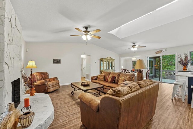 living room with a fireplace, hardwood / wood-style floors, ceiling fan, and lofted ceiling