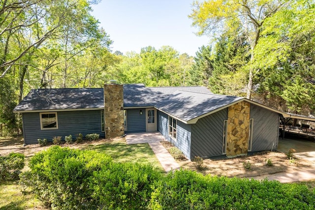 mid-century modern home featuring stone siding and a chimney