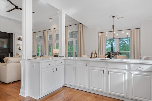 kitchen with white cabinets, pendant lighting, light wood-type flooring, and sink