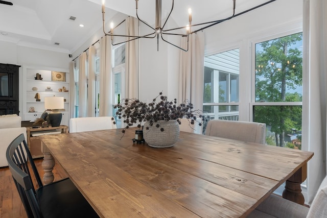 dining area featuring crown molding, built in features, and a notable chandelier