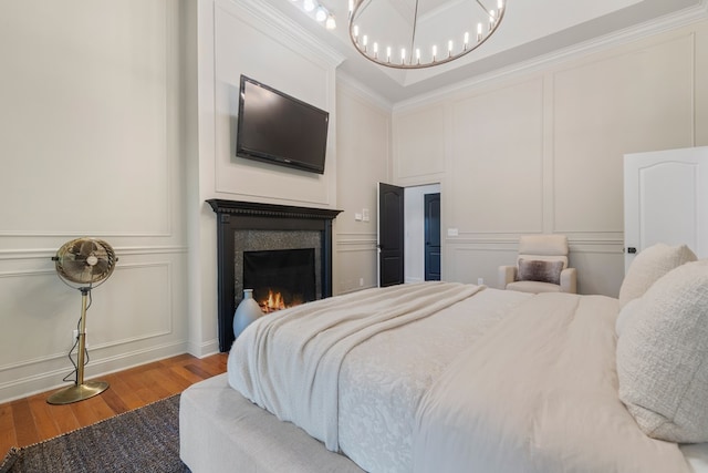 bedroom with hardwood / wood-style floors, an inviting chandelier, and ornamental molding