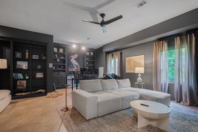 living room with built in shelves, ceiling fan, a healthy amount of sunlight, and a textured ceiling