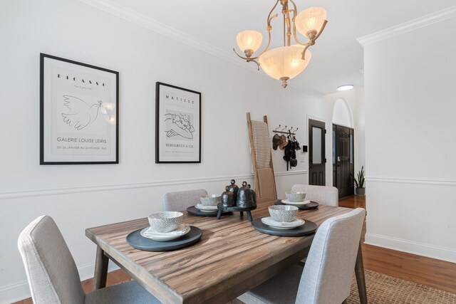 dining room featuring wood-type flooring, crown molding, and a chandelier