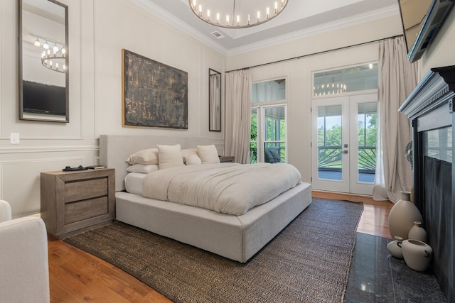 bedroom with access to exterior, french doors, an inviting chandelier, wood-type flooring, and ornamental molding