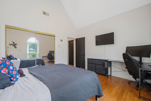 bedroom with a closet, high vaulted ceiling, and light hardwood / wood-style floors