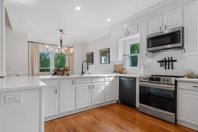 kitchen featuring sink, white cabinets, a notable chandelier, and appliances with stainless steel finishes