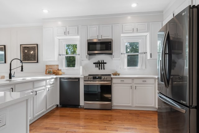 kitchen with white cabinets, sink, light wood-type flooring, and stainless steel appliances