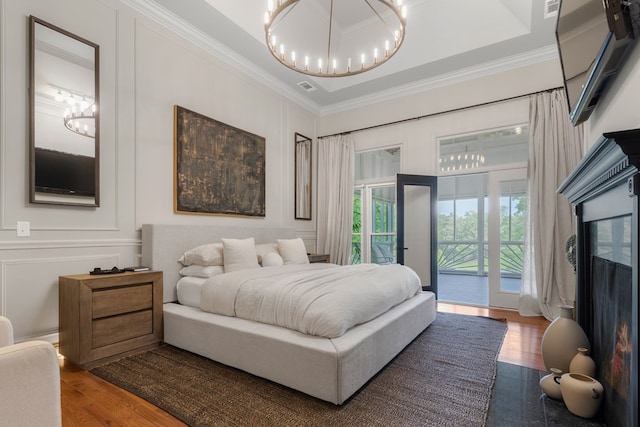 bedroom with hardwood / wood-style floors, access to exterior, and crown molding