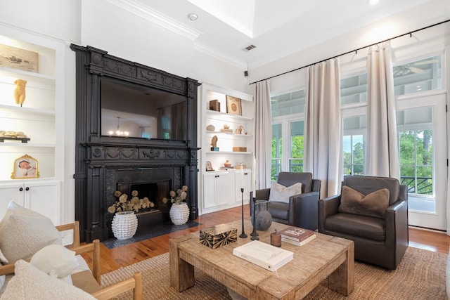 living room with light hardwood / wood-style floors, built in features, and ornamental molding