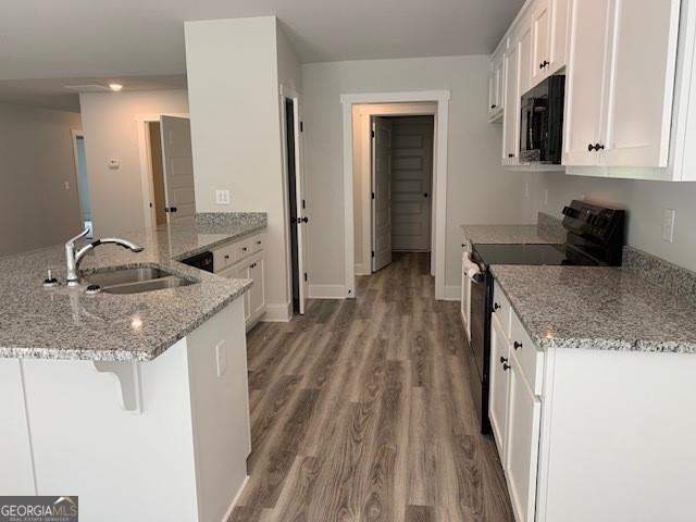 465 Riley Cir, Milledgeville, GA 31061 - kitchen with electric stove, a peninsula, white cabinets, light wood-style flooring, and light stone counters