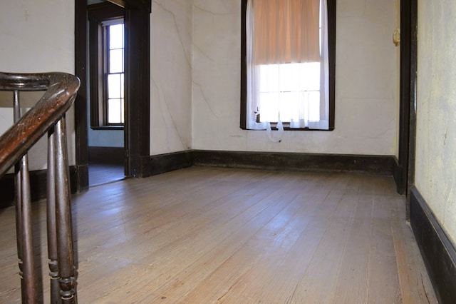 empty room with light hardwood / wood-style floors and a healthy amount of sunlight