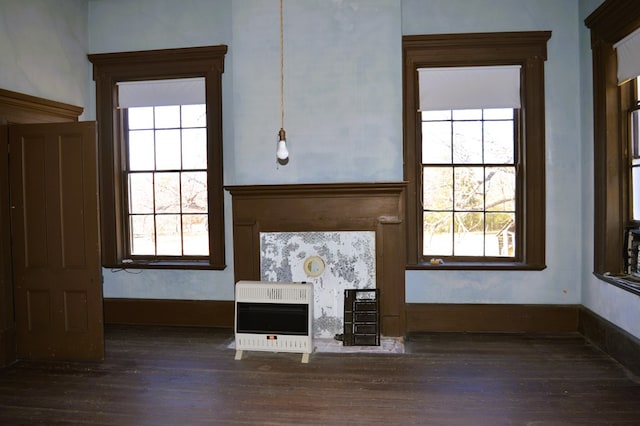 unfurnished living room featuring a healthy amount of sunlight, dark hardwood / wood-style flooring, and heating unit