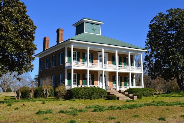 greek revival house with a front yard and a porch