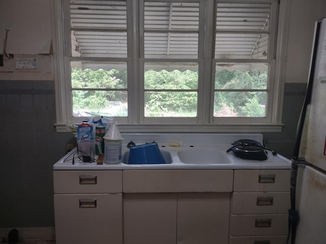 kitchen featuring stainless steel fridge and white cabinetry