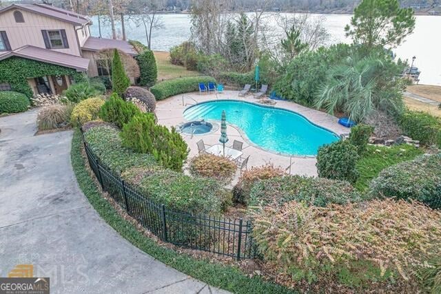 view of swimming pool featuring fence, a fenced in pool, a water view, and a patio