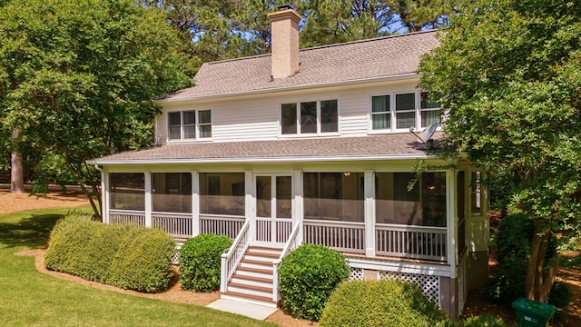 rear view of property featuring a sunroom, a chimney, roof with shingles, and stairs