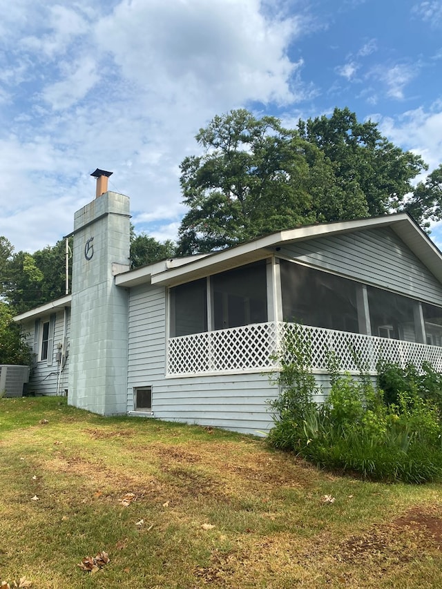 view of home's exterior with a sunroom and a yard