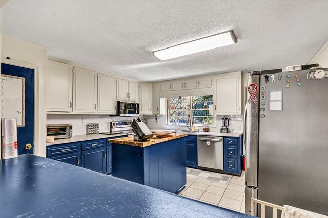 100 Cross Plains Hulett Rd, Carrollton, GA 30016 - kitchen with white cabinetry, butcher block countertops, light tile patterned floors, blue cabinets, and appliances with stainless steel finishes