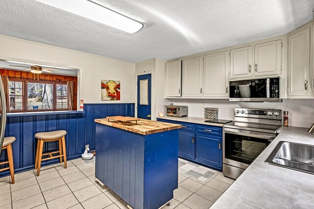 100 Cross Plains Hulett Rd, Carrollton, GA 30016 - kitchen featuring a kitchen island, blue cabinets, appliances with stainless steel finishes, light tile patterned floors, and wood counters