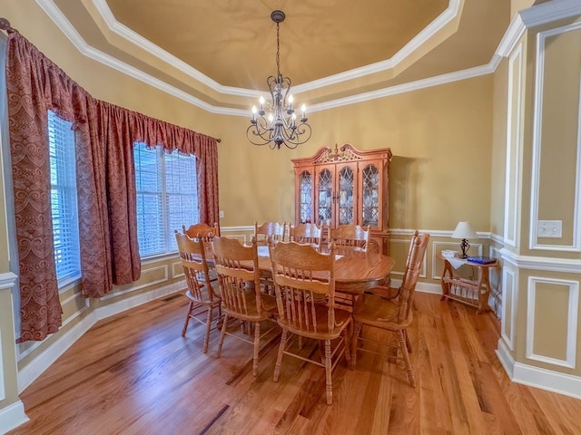 dining space with an inviting chandelier, a tray ceiling, and light hardwood / wood-style floors